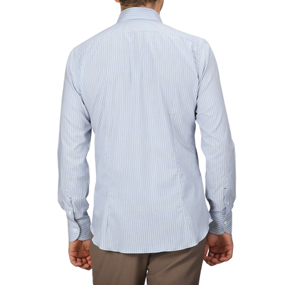 A person is wearing the Denim Blue Striped Cotton BD Regular Shirt from Mazzarelli with brown pants, facing away from the camera to highlight its regular fit and hand-stitched pleated shoulder details.