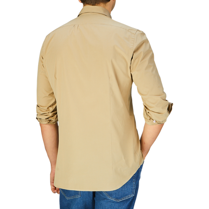 Man standing with his back facing the camera, wearing a Mazzarelli Khaki Beige Cotton Gabardine Regular Fit Shirt and blue jeans.