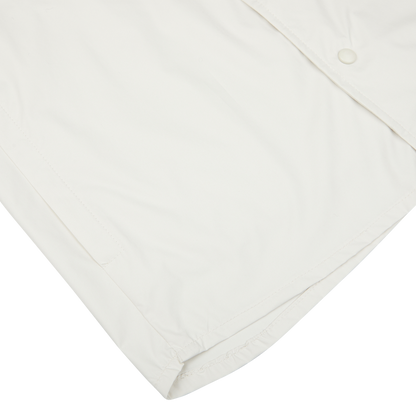 A close-up of a cream-colored, water-resistant nylon Mazzarelli technical overshirt with a snap button and visible stitching.