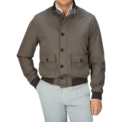 Man wearing a luxurious, olive green Moorer Technical Nylon Blouson with button detail over a light-colored shirt and pale pants.