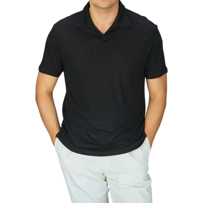 A man wearing a breathable Paige Black Linen Capri Collar Polo Shirt and white linen pants.