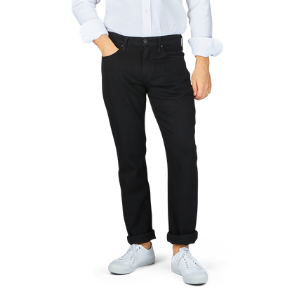 Man wearing Paige Black Shadow Cotton Transcend Normandie Jeans with a white shirt and white sneakers.
