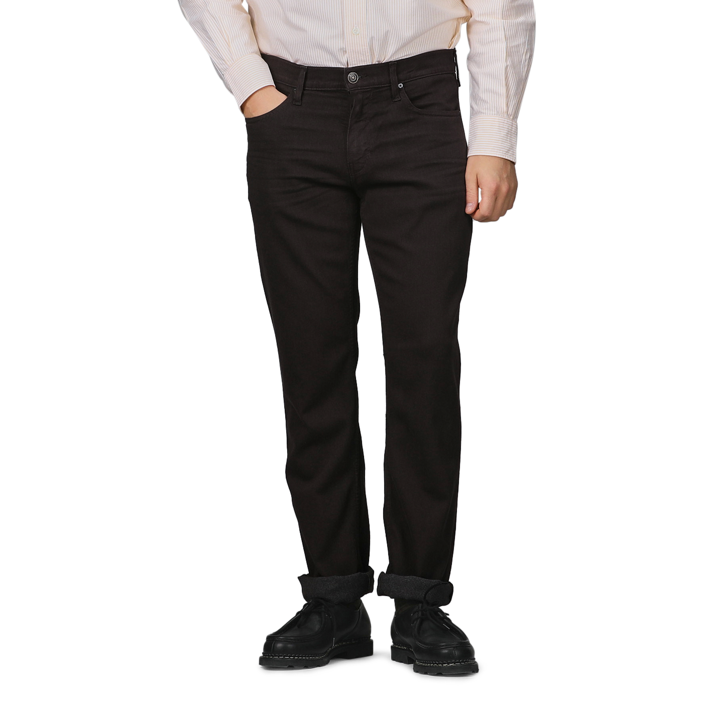 Wearing a white shirt and black shoes, a person stands against a plain background, embodying the elegance of Paige's Brown Cotton Transcend Normandie Jeans with folded cuffs.