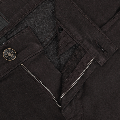 Close-up of a partially unzipped dark brown pair of Paige's Brown Cotton Transcend Normandie Jeans, highlighting the straight leg design with a metal button and intricate stitching details, crafted from advanced Transcend fabric.
