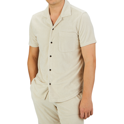 A person wearing a Cream Beige Cotton Towelling Polo Shirt by Paige with a front pocket and matching pants stands against a plain gray background.