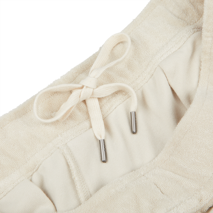 Close-up image of a beige garment, Cream Beige Cotton Towelling Shorts made from a soft towelling cotton blend by Paige, with an adjustable drawstring waist featuring metal aglets.