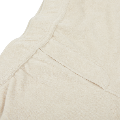Close-up view of a beige fabric with a seam and an overlapping flap, displaying a soft texture, perfect for summer shorts crafted from a towelling cotton blend. The Cream Beige Cotton Towelling Shorts by Paige exemplify this ideal material.