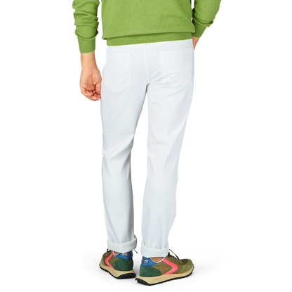 Person wearing white Paige Icecap White Cotton Transcend Federal Slim Jeans and colorful sneakers standing against a neutral background.