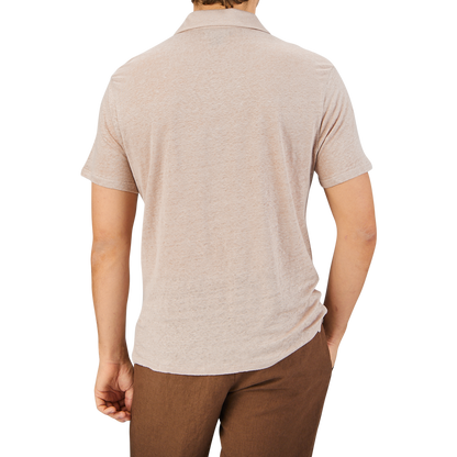 Rear view of a man wearing a Paige Light Pink Linen Capri Collar Polo Shirt and brown pants, standing against a plain grey background.