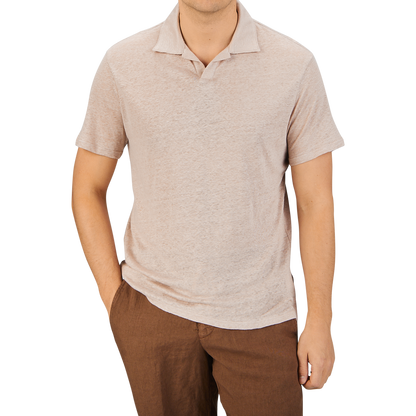 Man in a Paige light pink linen Capri collar polo shirt and brown pants standing against a gray background.