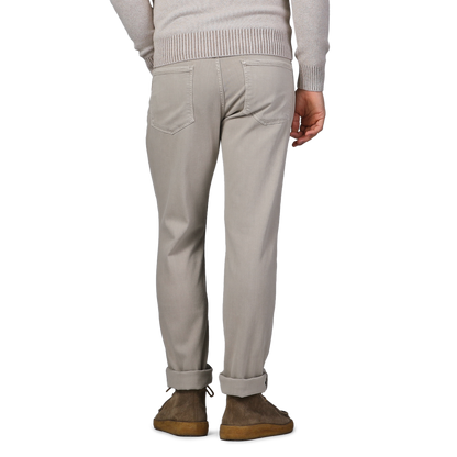 An individual is seen from behind, dressed in Paige's Moroccan Clay Cotton Transcend Federal Slim Jeans paired with a cozy, light-colored sweater.