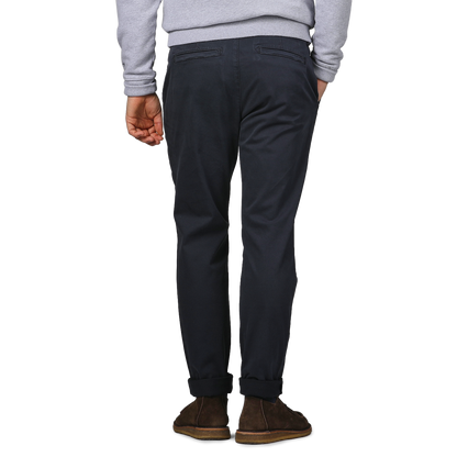 A person wearing a gray sweatshirt and relaxed Paige Navy Blue Danford Cotton Chinos stands with their back to the camera, hands at their sides.