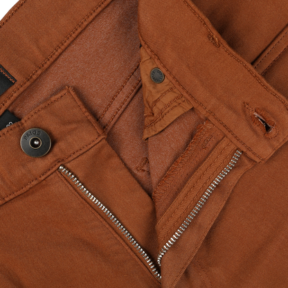 Close-up of Paige Rust Brown Cotton Transcend Federal Slim Jeans showcasing the waistband, zipper, button, and clasp. The partially undone zipper reveals the inside fabric. These jeans deliver a comfortable fit with their high-quality Transcend fabric.