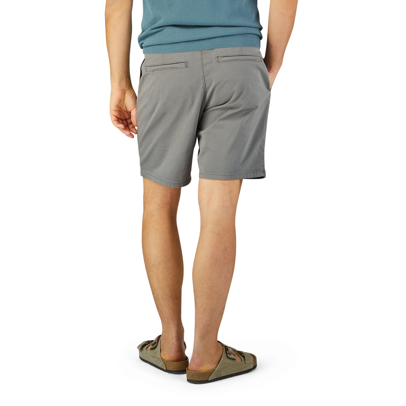A man wearing Paige's slate grey cotton blend Phillips shorts and beige slip-on shoes stands with his back to the camera against a blue and yellow background.