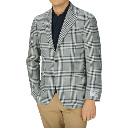 A man wearing a Ring Jacket Blue Green Glen Check Balloon Wool blazer, beige pants, and a dark shirt, photographed from neck to waist against a grey background.