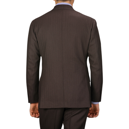 A person wearing a Brown Herringbone Calm Twist Wool Suit by Ring Jacket, including the suit jacket and matching trousers, viewed from the back.