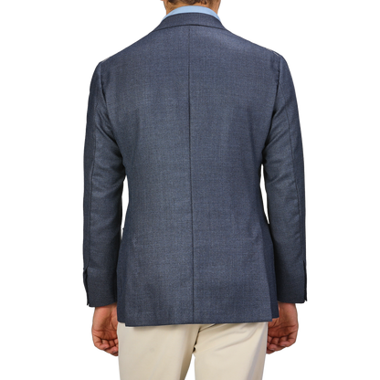 A person is shown from the back, wearing a Denim Blue Wool Balloon Travel Blazer by Ring Jacket in an elegant blazer style with beige pants.