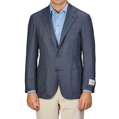 A person wearing the Ring Jacket Denim Blue Wool Balloon Travel Blazer over a light blue shirt and beige pants, with a visible tag on the sleeve, exuding an air of relaxed sophistication.