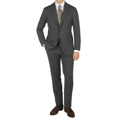 A man wearing a dark grey Ring Jacket high twist wool suit with a notched lapel, light green tie, white shirt, and brown shoes, standing against a plain background.