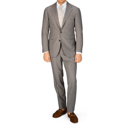 Man standing in a Ring Jacket Mid Grey High-Twist Wool suit with a light shirt and brown shoes.