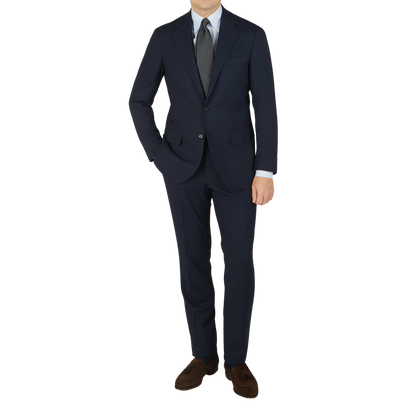 A man in a Ring Jacket Navy Blue High Twist Wool Suit, white shirt, and gray tie, standing against a light background.