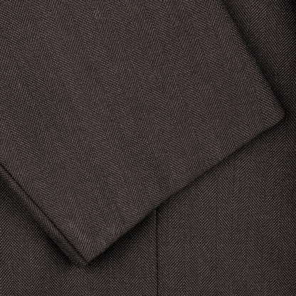 Close-up of the Brown Herringbone Calm Twist Wool Suit by Ring Jacket, showcasing its dark brown fabric with overlapping edges.