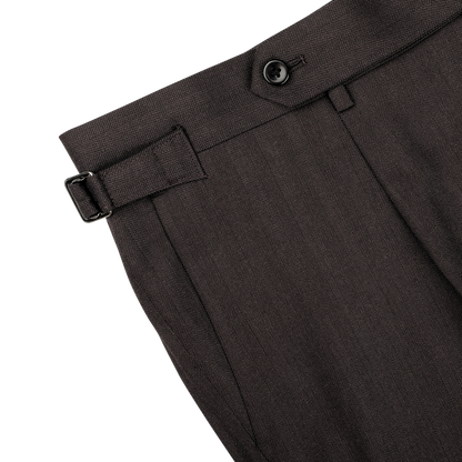 Close-up of a pair of dark brown dress pants from Ring Jacket's Brown Herringbone Calm Twist Wool Suit, crafted from high-twist wool fabric and highlighting the waistband with a black decorative button, belt loop, and adjustable side buckle.