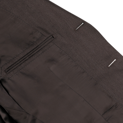 A close-up view of neatly stitched dress pants from the Brown Herringbone Calm Twist Wool Suit by Ring Jacket, showcasing the refined details of the back pocket and belt loops, crafted from high-twist wool fabric.
