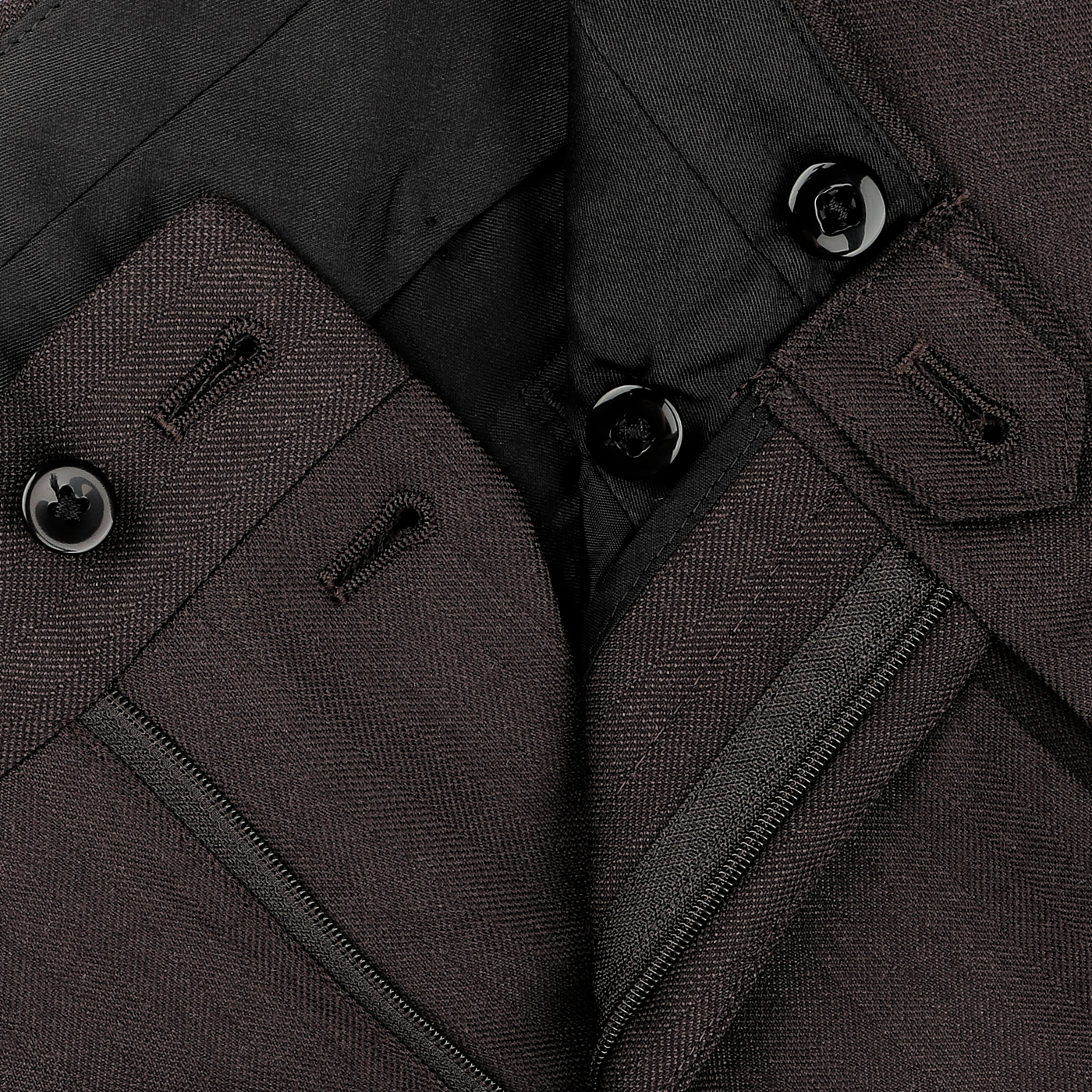 Close-up of the Brown Herringbone Calm Twist Wool Suit from Ring Jacket, showcasing dark brown trousers with visible buttons, buttonholes, and a zipper on the waistband, expertly crafted from high-twist wool fabric.