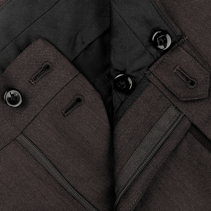 Close-up of the Brown Herringbone Calm Twist Wool Suit from Ring Jacket, showcasing dark brown trousers with visible buttons, buttonholes, and a zipper on the waistband, expertly crafted from high-twist wool fabric.