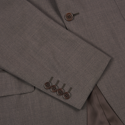 Close-up of the Canali Dark Brown Tropical Wool Suit shows a men’s brown jacket sleeve with four matching cuff buttons, textured wool fabric, two front buttons, a pocket flap, and visible brown satin lining. , available at Richard Gelding Mayfair