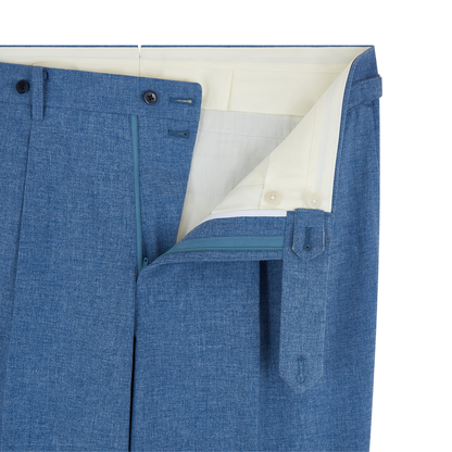 Close-up of Ring Jacket's Pale Blue Melange Tropical Wool/Cotton/Silk Suit trousers with front flap open, revealing a white lining, light blue zipper, double-button closure, and right-side extended waistband tab with button and belt loop. , available at Richard Gelding Mayfair