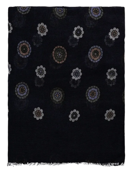 The Amanda Christensen Navy Flower Medallion Linen Scarf features a dark navy base with a repeating floral medallion pattern in white, gray, purple, and brown tones. Finished with a frayed fringe. , available at Richard Gelding Mayfair