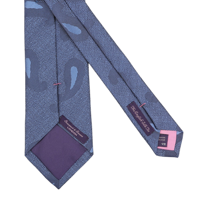 The Blue Paisley Woven Silk Tie by Seaward & Stearn is crafted from luxurious silk and features the labels "Sevenfold," "100% Silk," and "Hand Made in Italy." This exquisite piece represents the elegance of Seaward & Stearn's handmade silk ties, promising a sophisticated touch to any ensemble.