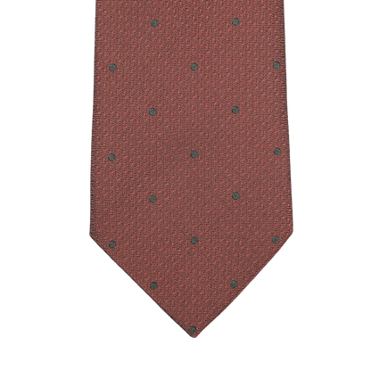 A close-up of the Brick Orange Dot Silk Tie by Seaward & Stearn, featuring a textured design with small black polka dots.
