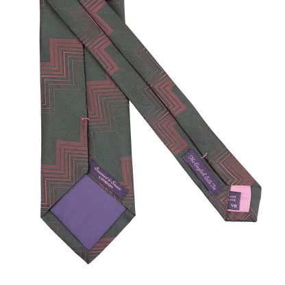 This Dark Green Herringbone Zigzag Silk Tie by Seaward & Stearn, handmade in England, features a geometric zigzag pattern in dark green and purple with tags on the reverse side.