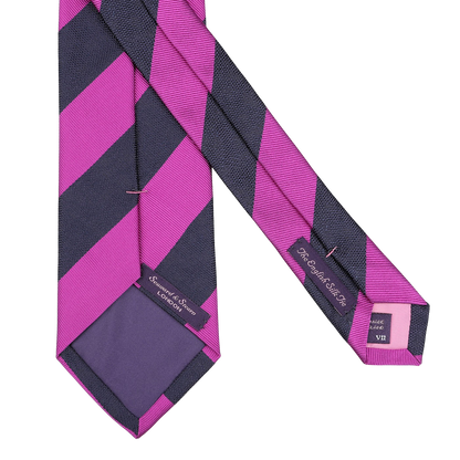 The Seaward & Stearn Fuschia Blue Striped Silk Tie, handmade in England, features diagonal purple and pink stripes with a label and care tag on the reverse side.