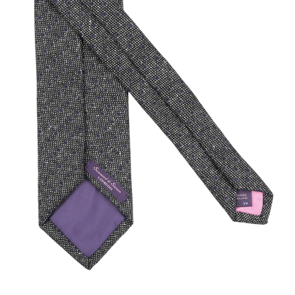 The Grey Blue Dot Wool Tie by Seaward & Stearn showcases a gray pattern with a purple lining, crafted from pure wool and featuring tags with brand details. Handmade in England, it combines elegance with a touch of distinction.