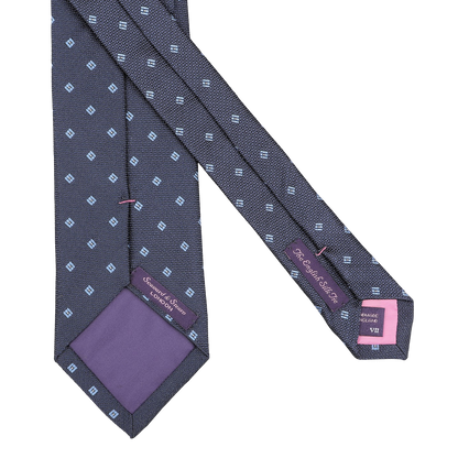Introducing the Seaward & Stearn Navy Blue Diamond Woven Silk Tie, exquisitely handmade with a sophisticated design of small light blue square patterns and accented by a hint of purple fabric on the inner tip, perfect for enhancing your style.