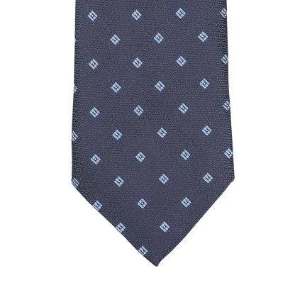 The Seaward & Stearn Navy Blue Diamond Woven Silk Tie is a handmade silk masterpiece, showcasing a navy blue color with an intricate pattern of small light blue square motifs.