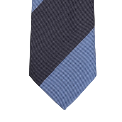 A close-up of the Seaward & Stearn Navy Blue Striped Silk Tie highlights a diagonal design with navy blue and dark gray sections against a light gray background, exemplifying the elegance of this handmade silk necktie.