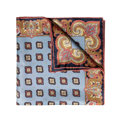 The Cardo Light Blue Silk Pocket Square by Sera Fine Silk features a folded square scarf with a paisley and geometric design in shades of blue, red, orange, and yellow, complemented by hand-rolled edges.