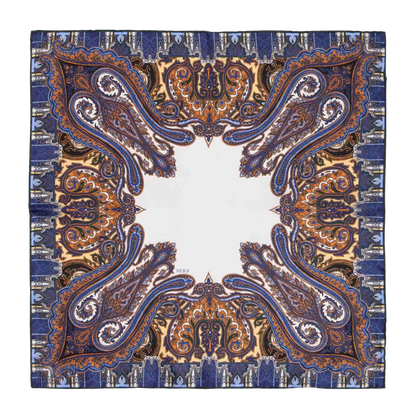 The Cortina Blue Silk Pocket Square by Sera Fine Silk showcases an intricate paisley pattern in shades of blue, orange, and gold, with a central white area and exquisite hand-rolled edges.