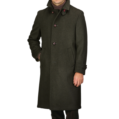 A man wearing the Dark Green Wool Alpaca Loden Coat by Steinbock, crafted from a premium wool-alpaca blend, showcases leather football buttons and practical side pockets.