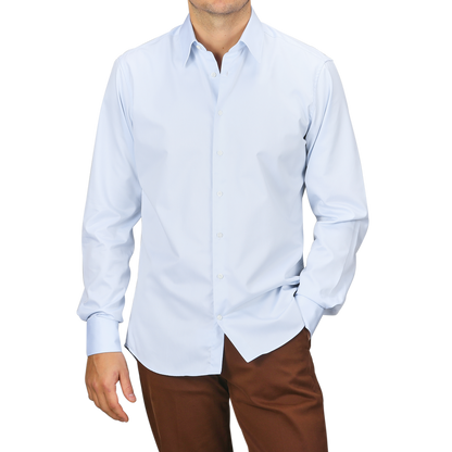 A person wearing the Stenströms Light Blue Cotton Twill Fitted Body Shirt paired with brown pants poses with one hand in the pocket against a plain background.