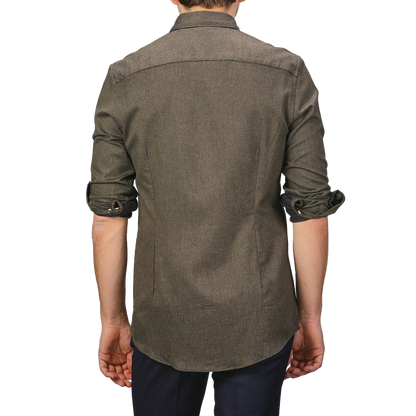 The image shows the back of a person wearing a slimline cut, long-sleeved shirt with rolled-up sleeves and dark pants. The shirt, the Moss Green Cotton Flannel Cut-Away Slimline Shirt by Stenströms, crafted from brushed cotton twill, adds a touch of sophistication to the casual look.