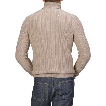 Rear view of a person wearing the Taupe Beige Structured Merino Rollneck by Stenströms, potentially part of a versatile capsule collection, paired with blue jeans.