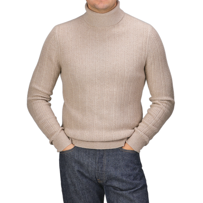 Person wearing a Taupe Beige Structured Merino Rollneck by Stenströms and dark jeans with hands in pockets, standing against a plain background.