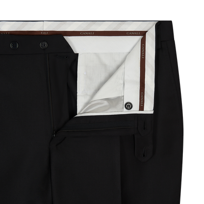 Close-up of the Canali Black Serge Wool Pleated Trouser with the waistband open, showing a white lining with brown trim and branding, plus a zipper fly, two inner buttons, and hook-and-bar closure. , available at Richard Gelding Mayfair