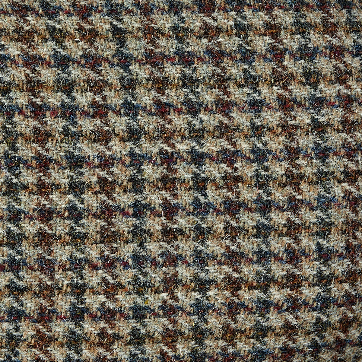 A close up of a Beige Houndstooth Harris Tweed Ivy Contemporary Cap, featuring a Wigéns pattern.